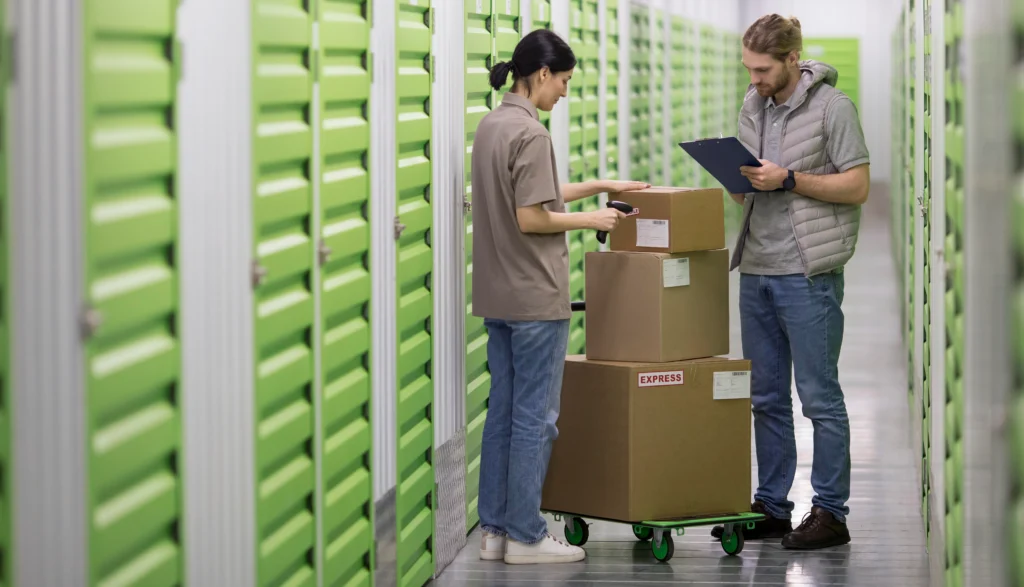 A man stands inside an empty 10×10 storage unit, smiling while looking at a tablet.