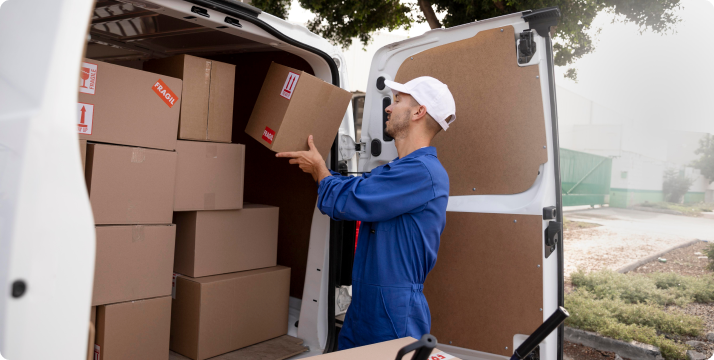 Mover loading cardboard boxes into a van during relocation service.