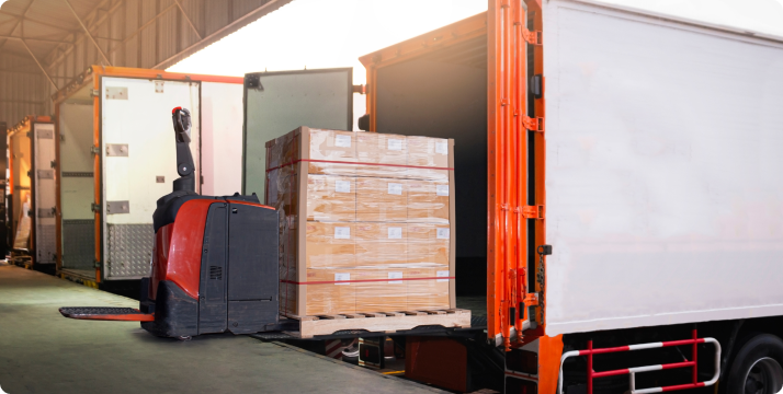 A forklift is parked beside a truck loaded with boxes, indicating a loading or unloading operation in progress.