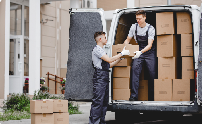 Two movers unloading cardboard boxes from a van outside a building.