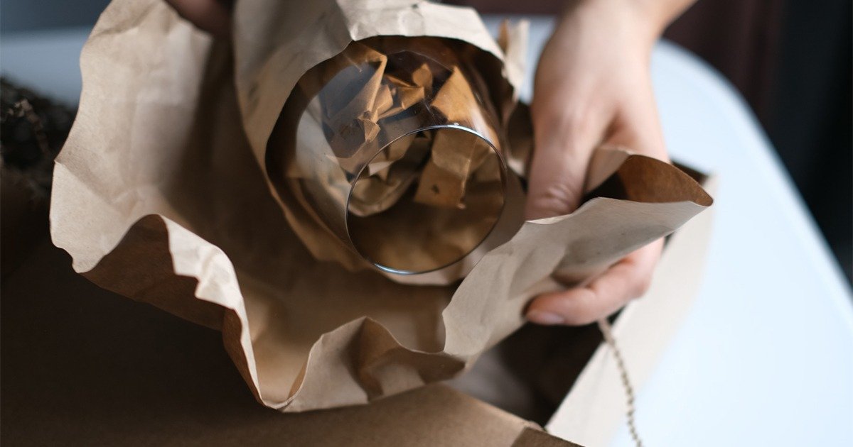 A person with a brown paper bag featuring a glass, showcasing effective methods for packing glasses during a move.