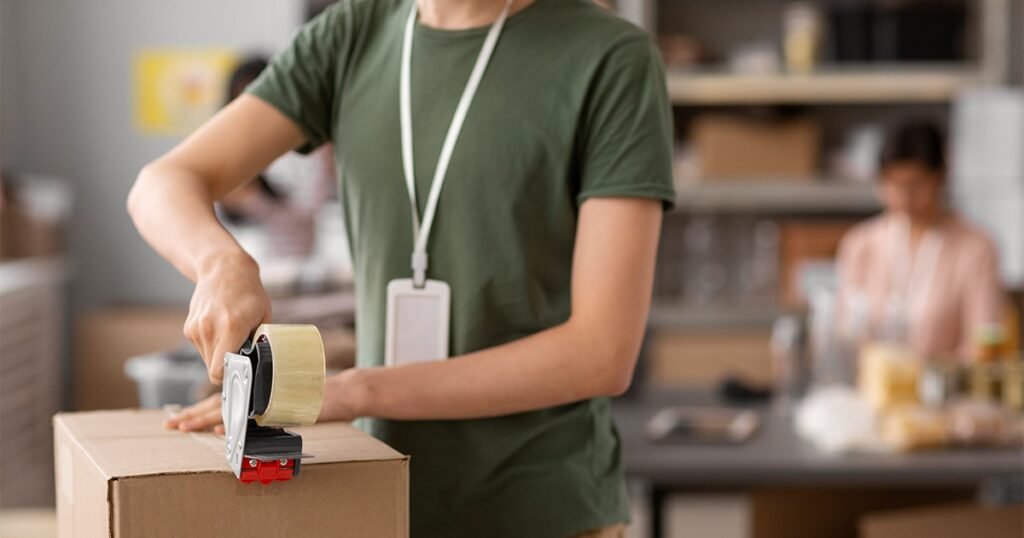 A man holds a taped box, suggesting a focus on professional packing services.