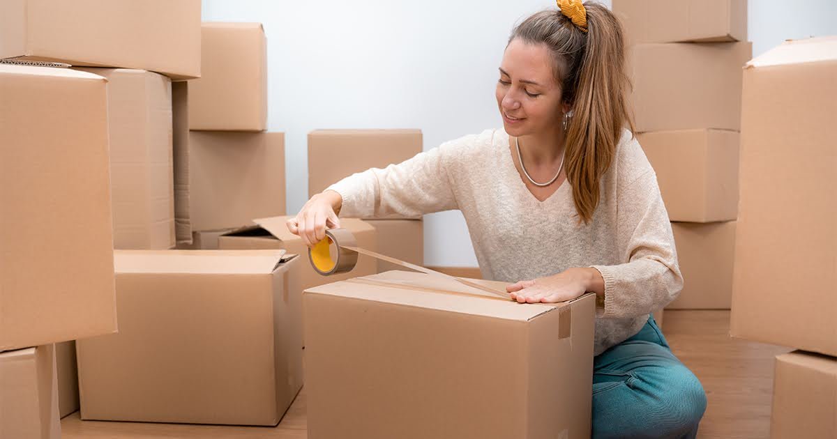 A woman organizes boxes in a vacant room, demonstrating practical packing tips for a smooth moving process.