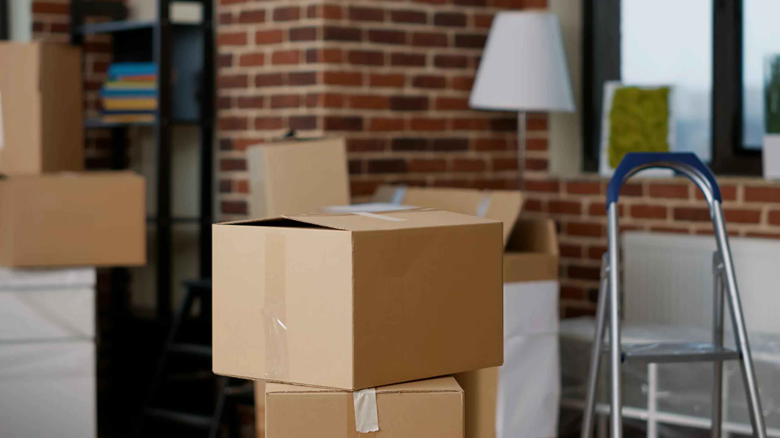 Man taping cardboard box while woman holds another moving box.